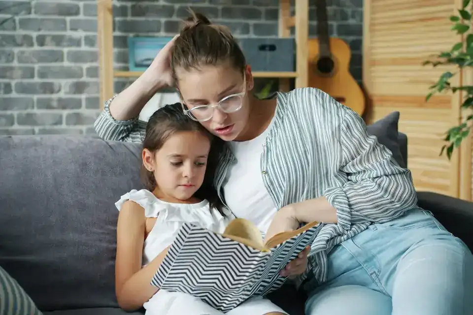 Mutter und Tochter lesen gemeinsam auf dem Sofa